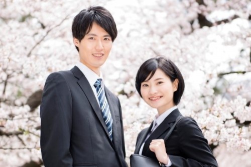 桜をバックにする男女の新入社員