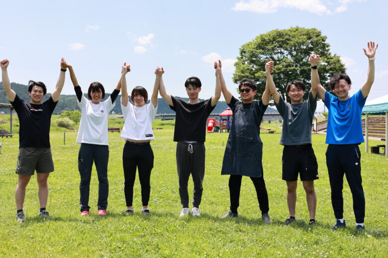 仲間たちと一緒に草原でバンザイをしている